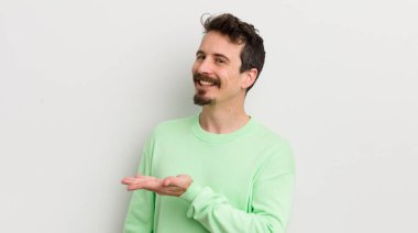 Genç yakışıklı adam neşeyle gülümsüyor, mutlu hissediyor ve bir konsept gösteriyor.