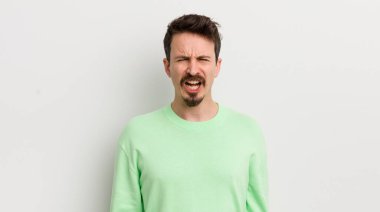 Genç yakışıklı adam agresif bir şekilde bağırıyor, çok sinirli görünüyor.