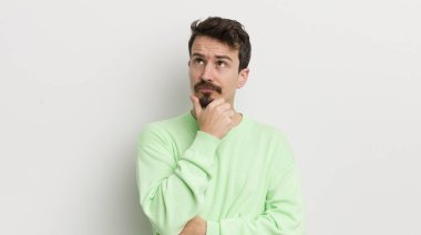 Genç yakışıklı adam düşünüyor, kuşkulu ve şaşkın hissediyor.