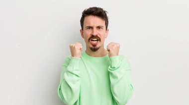 Genç yakışıklı adam sinirli bir ifadeyle agresif bir şekilde bağırıyor.