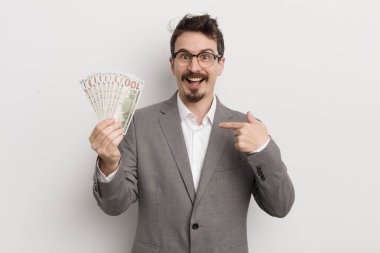 Genç ve yakışıklı bir adam mutlu hissediyor ve heyecanla kendini işaret ediyor. İş adamı ve banknotlar
