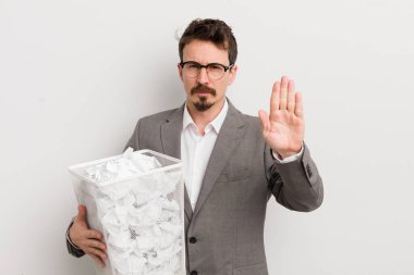 Genç ve yakışıklı adam ciddi görünüyor. Avuç içi gösteriyor. Durdurma hareketi yapıyor. Kağıt toplar sepeti konsepti