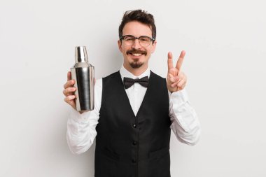 Genç yakışıklı adam gülümsüyor ve mutlu görünüyor, zafer ya da barış işareti yapıyor. Kokteyl barmeni