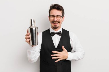 Genç yakışıklı bir adam komik bir şakaya yüksek sesle gülüyor. Kokteyl barmeni