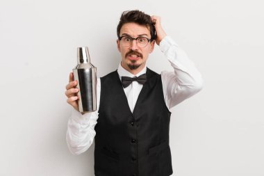 Genç ve yakışıklı bir adam stresli, endişeli ya da korkmuş hissediyor. Elleri başının üstünde. Kokteyl barmeni