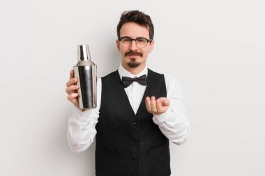 Genç ve yakışıklı bir adam arkadaşça gülümsüyor ve bir konsept sunuyor. Kokteyl barmeni