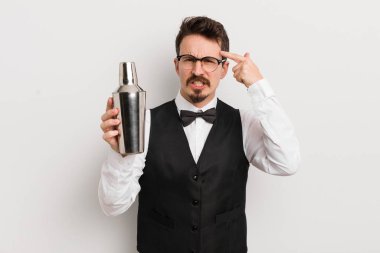 Genç yakışıklı adam kafası karışık ve şaşkın hissediyor, deli olduğunu gösteriyor. Kokteyl barmeni