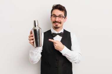 Genç yakışıklı adam neşeyle gülümsüyor, mutlu hissediyor ve bir tarafı işaret ediyor. Kokteyl barmeni