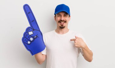 Genç ve yakışıklı bir adam mutlu hissediyor ve heyecanla kendini işaret ediyor. Bir numaralı el konsepti