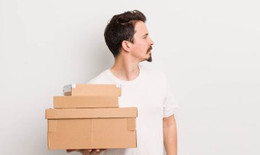 Profilde genç yakışıklı bir adam hayal kuruyor, hayal kuruyor ya da hayal kuruyor. nakliye kutuları kavramı