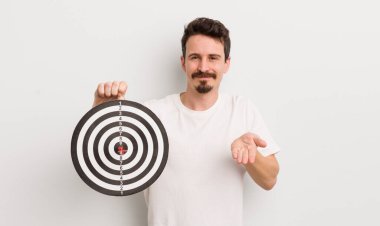 Genç ve yakışıklı bir adam arkadaşça gülümsüyor ve bir konsept sunuyor. dart hedef konsepti