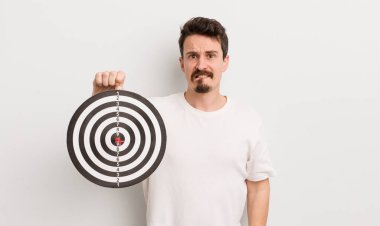 Kafası karışmış ve kafası karışmış genç yakışıklı bir adam. dart hedef konsepti