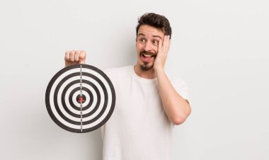 Genç yakışıklı adam mutlu, heyecanlı ve şaşırmış hissediyor. dart hedef konsepti