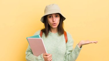 Genç İspanyol kadın şaşırmış ve şok olmuş görünüyor. Çenesi düşmüş ve elinde bir nesne tutuyor. öğrenci konsepti