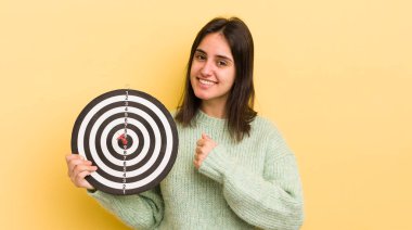 Genç İspanyol kadın kendini mutlu hissediyor ve bir meydan okumayla yüzleşiyor ya da kutluyor. dart hedef kavramı