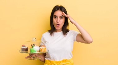 Genç İspanyol kadın mutlu, şaşkın ve şaşırmış görünüyor. Ev yapımı kek konsepti