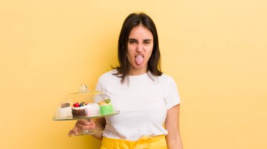 Genç İspanyol kadın iğreniyor, sinirleniyor ve dili dışarı çıkıyor. Ev yapımı kek konsepti