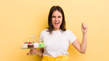 Genç İspanyol kadın öfkeli bir ifadeyle agresif bir şekilde bağırıyor. Ev yapımı kek konsepti