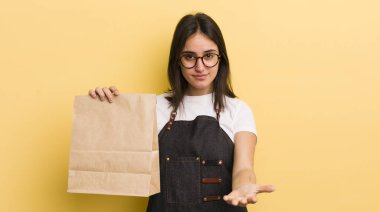 Genç İspanyol kadın mutlu bir şekilde gülümsüyor ve bir konsept sunuyor. Fast food konsepti