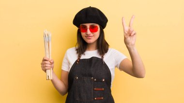 Genç İspanyol kadın gülümsüyor ve mutlu görünüyor, zafer ya da barış işareti yapıyor. sanatçı konsepti