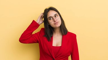 Genç İspanyol kadın şaşkın ve kafası karışık, kaşınan bir kafa hissediyor. iş kavramı