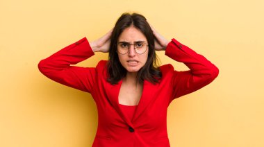 Genç İspanyol kadın stresli, endişeli ya da korkmuş hissediyor, elleri başının üstünde. iş kavramı