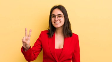 Genç İspanyol kadın gülümsüyor ve mutlu görünüyor, zafer ya da barış işareti yapıyor. iş kavramı