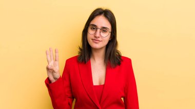 Genç İspanyol kadın gülümsüyor ve arkadaş canlısı görünüyor, üç numarayı gösteriyor. iş kavramı