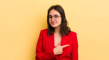 Genç İspanyol kadın neşeyle gülümsüyor, mutlu hissediyor ve bir tarafı işaret ediyor. iş kavramı