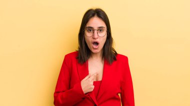 Genç İspanyol kadın şok olmuş ve ağzı açık, kendini işaret ederek şaşırmış görünüyor. iş kavramı