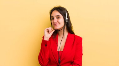 Genç İspanyol kadın mutlu ve kendinden emin bir ifadeyle gülümsüyor. Elleri çenesinde. tele pazarlamacı kavramı