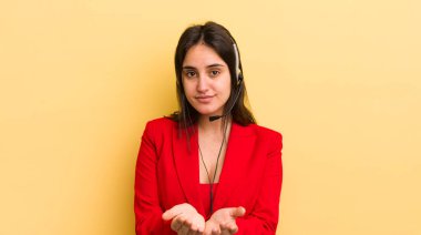 Genç İspanyol kadın mutlu bir şekilde gülümsüyor ve bir konsept sunuyor. tele pazarlamacı kavramı