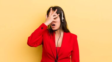 Genç İspanyol bir kadın şok olmuş, korkmuş ya da korkmuş görünüyor. Yüzü elle kapatılmış. tele pazarlamacı kavramı