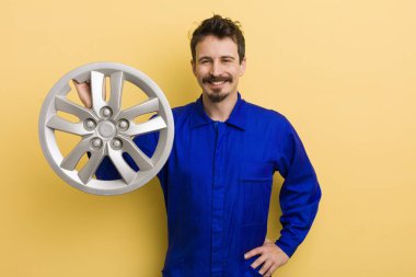 Adam mutlu bir şekilde gülümsüyor, eli kalçasında ve kendinden emin. araba tamircisi konsepti