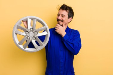 Mutlu, kendinden emin ve elleri çenesinde gülümseyen bir adam. araba tamircisi konsepti