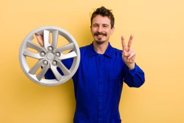 Gülümseyen ve mutlu görünen bir adam zafer ya da barış işareti yapar. araba tamircisi konsepti