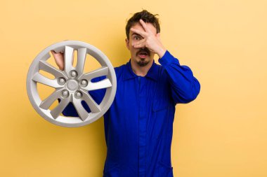 Adam şok olmuş, korkmuş ya da korkmuş görünüyor, yüzünü eliyle kapatıyor. araba tamircisi konsepti