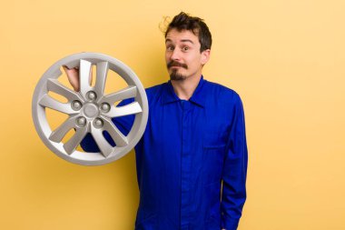 Adam omuz silkiyor, kafası karışık ve kararsız hissediyor. araba tamircisi konsepti