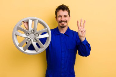 Adam gülümsüyor ve arkadaş canlısı görünüyor, üç numarayı gösteriyor. araba tamircisi konsepti