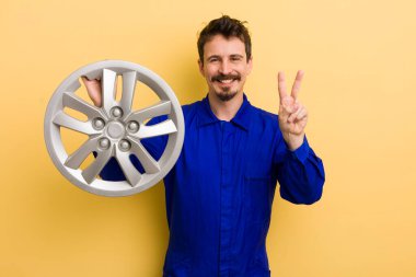 Adam gülümsüyor ve dost canlısı görünüyor, iki numarayı gösteriyor. araba tamircisi konsepti