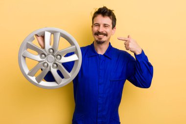 Adam kendine güvenerek kendi gülüşünü işaret ediyor. araba tamircisi konsepti