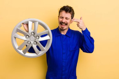 Adam mutsuz ve stresli görünüyor, intihar jesti silah işareti yapıyor. araba tamircisi konsepti