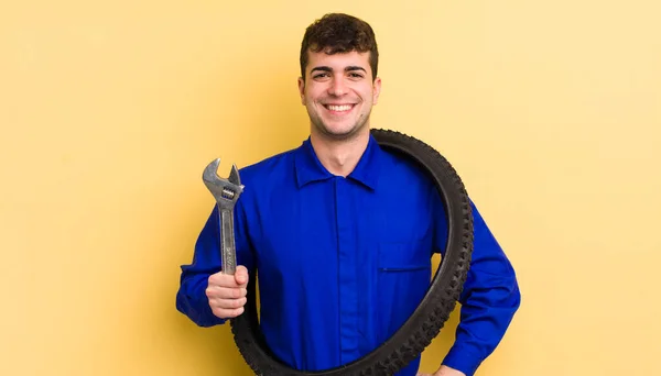 若いハンサムな男が喜んで笑顔で手を腰と自信を持って 自転車修理工のコンセプト — ストック写真