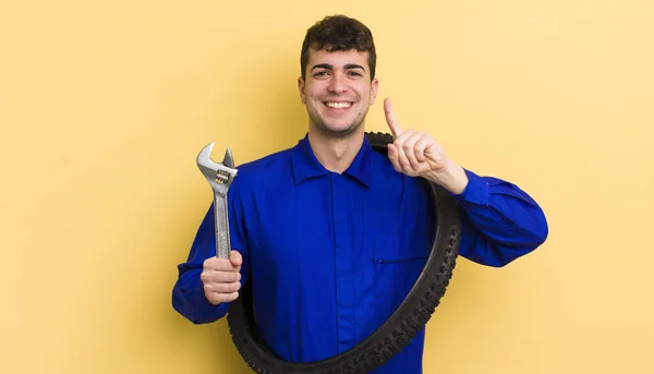 誇らしげに笑顔で自信を持ってナンバーワンを作っている若いハンサムな男 自転車修理工のコンセプト — ストック写真