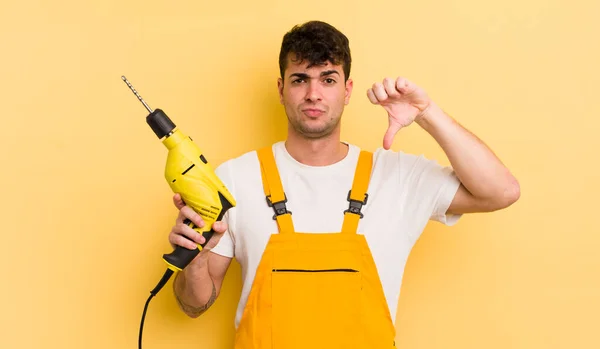 Jovem Bonito Homem Sentindo Cruz Mostrando Polegares Para Baixo Handyman — Fotografia de Stock