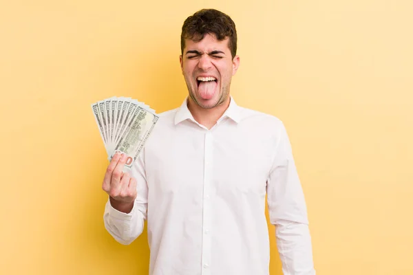 陽気で反抗的な態度を持つ若いハンサムな男冗談と舌を突き出す お金の概念 — ストック写真