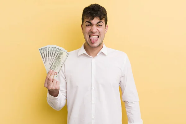 若いハンサムな男はうんざりしていらいらして舌を出す お金の概念 — ストック写真