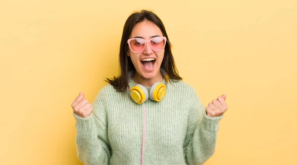 若いヒスパニック系の女性はショックを受けて笑って成功を祝います ヘッドフォンとサングラスのコンセプト — ストック写真