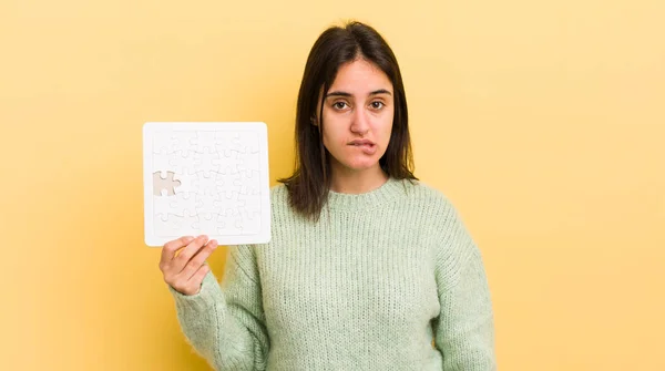 young hispanic woman looking puzzled and confused. puzzle concept