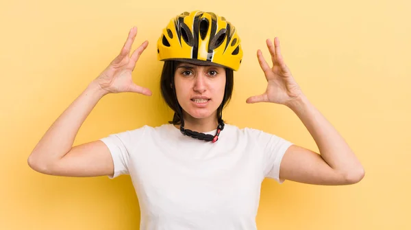 young hispanic woman feeling stressed, anxious or scared, with hands on head. bike helmet concept